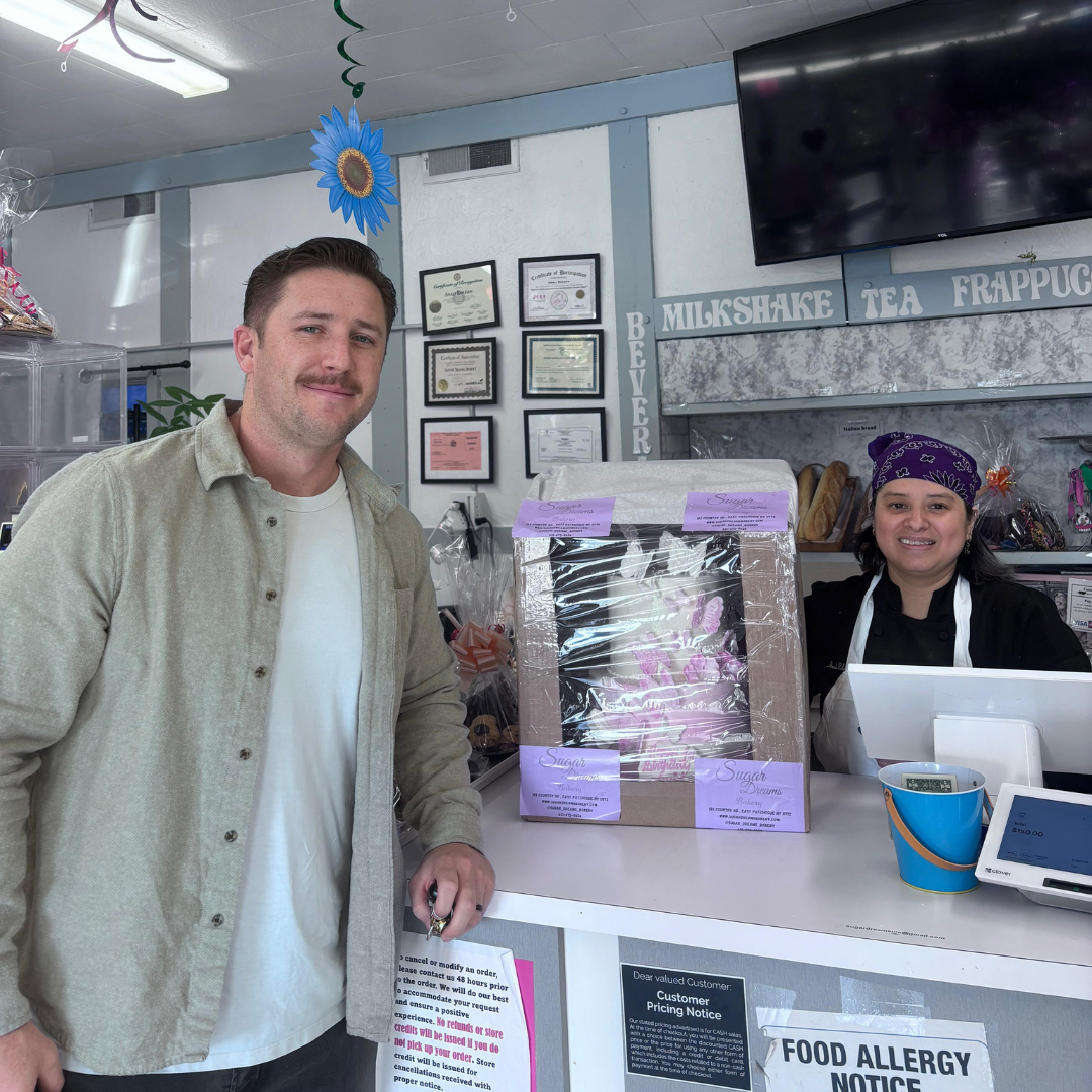 Happy customer with custom cake order at Sugar Dreams Bakery counter East Patchogue NY